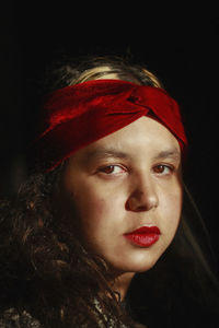 Close-up portrait of young woman against black background