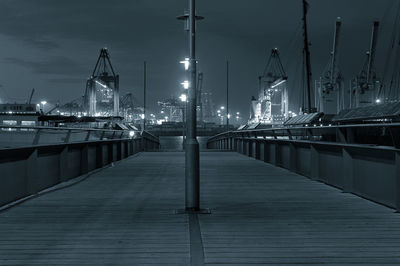 Illuminated street lights on bridge at commercial dock during night