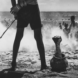 Low section of man standing on beach against sky