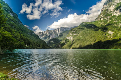 Scenic view of river by mountains against sky