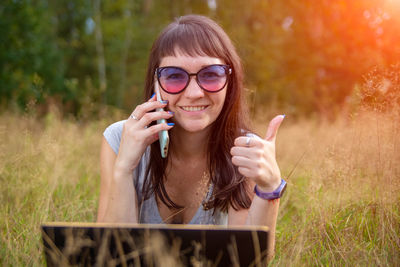 Portrait of young woman wearing sunglasses standing on field