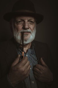 Man wearing hat and holding pipe against gray background