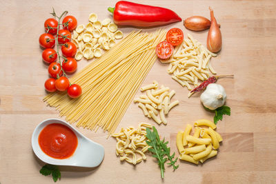 High angle view of pasta with tomatoes and red chili pepper on wooden table