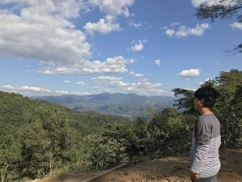 Side view of man standing on mountain against sky