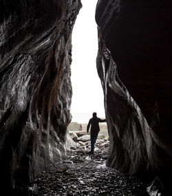 Rear view of man standing by rock formation