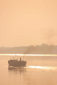 Silhouette boat in sea against sky during sunset