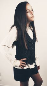 Young woman looking away while standing against white background