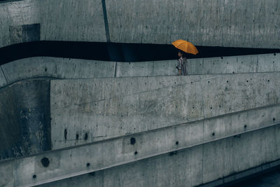 Woman with umbrella walking against wall