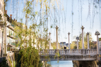 Woman standing on footbridge over canal in city