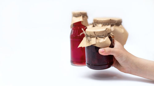 Close-up of hand holding drink against white background