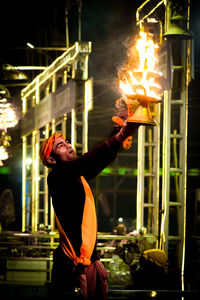 Rear view of woman holding fire in factory