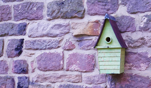 Close-up of birdhouse on stone wall