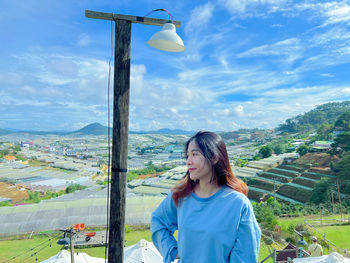 Portrait of young woman standing by sea against sky