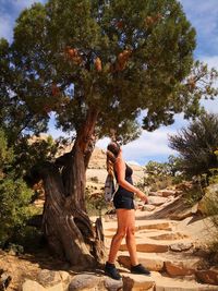 Full length of young woman standing by tree