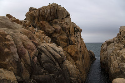 Rock formations in sea against sky