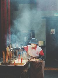 Man collecting burnt incenses in temple