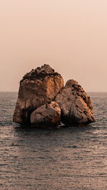 Rock formation in sea against clear sky