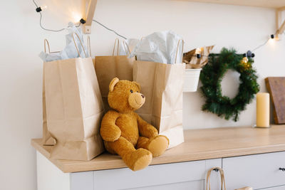 Soft toy bear near craft paper bags and christmas wreath