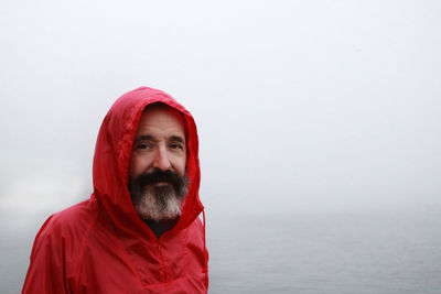 Portrait of man in red jacket against sea