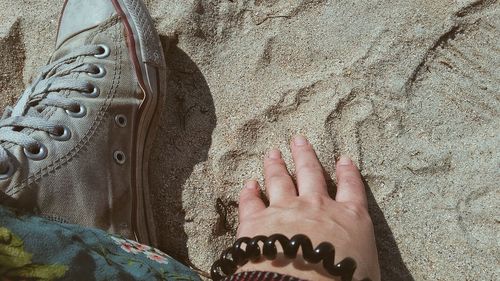 Low section of woman touching sand at beach