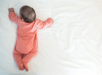 Rear view of baby girl lying on bed