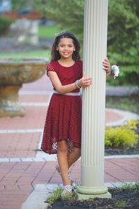 Portrait of smiling girl standing by column in park