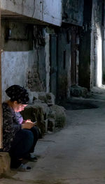 Full length of woman sitting against building