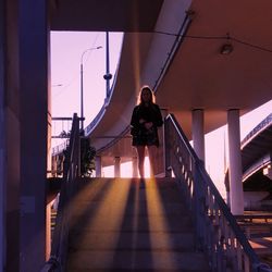 Rear view of woman on staircase by building against sky