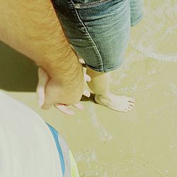 Cropped image of couple holding hands on shore