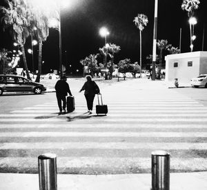 Rear view of people walking on road at night