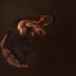Digital composite image of shirtless man holding pen over black background