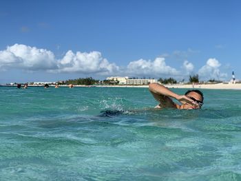 Men swimming in sea against sky