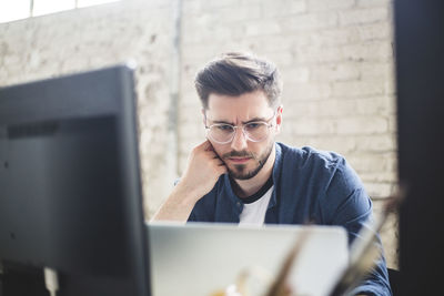 Male it professional thinking while working on computer codes in laptop at workplace