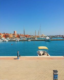 Sailboats in marina at harbor against clear blue sky