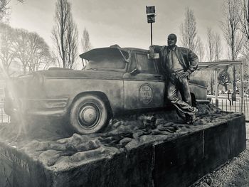 Man standing by car on road against sky