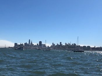 Scenic view of sea and buildings against clear blue sky