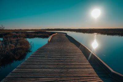 Pier over lake against sky during sunset