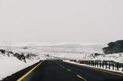 Road leading towards snow covered landscape