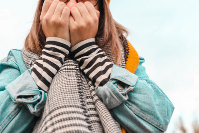 Midsection of woman with hands cupped against sky