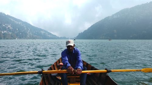 Man sitting on boat against sky