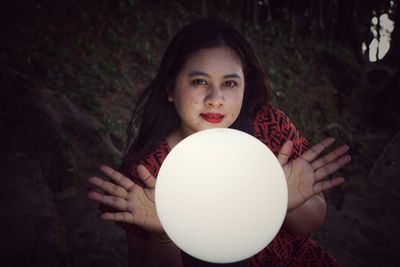 High angle portrait of woman holding illuminated lamp