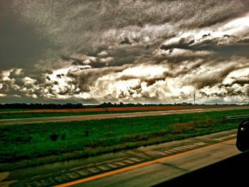 Country road against cloudy sky