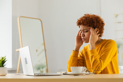 Young woman using mobile phone while sitting on table