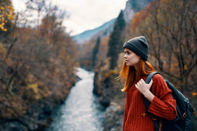 Young woman looking away while standing on tree during winter