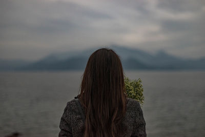 Rear view of woman by sea against sky