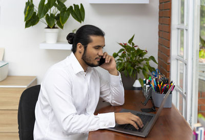 Young man using mobile phone while sitting on table