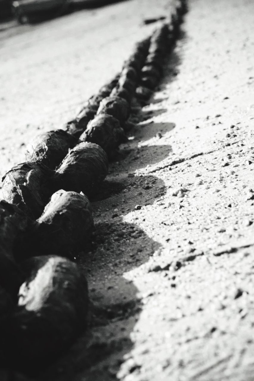 selective focus, surface level, street, beach, close-up, sunlight, sand, textured, wet, focus on foreground, road, shadow, transportation, day, outdoors, no people, asphalt, nature, high angle view, tranquility