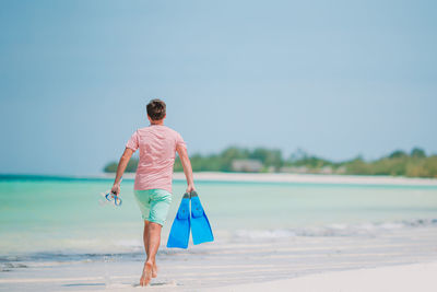 Rear view of man walking on beach