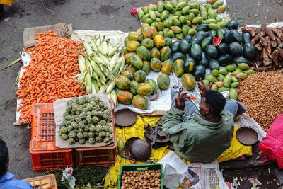 High angle view of vendor selling fruits and vegetables at market stall
