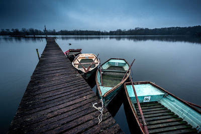 Pier over lake against sky with boats